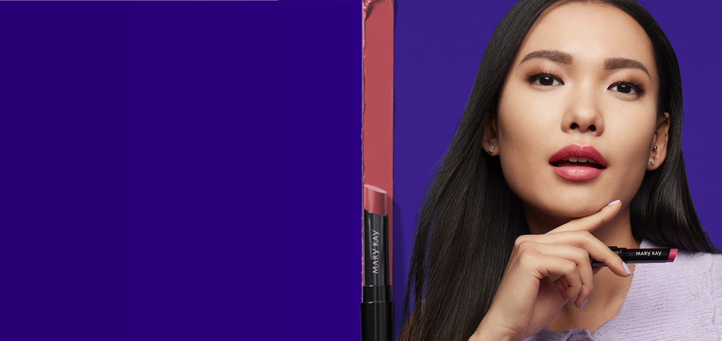 Against a dark purple background, a model holds a tube of lipstick and is pictured next to a vertical lipstick smear and tube.