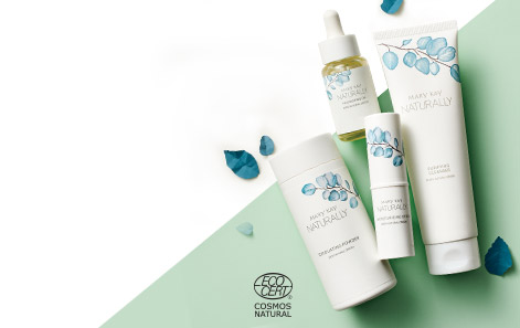 Mary Kay Naturally® products styled against a green and white background, with blue leaves sprinkled in.  