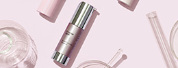 Closed bottle of Mary Kay TimeWise Repair Volu-Firm Advanced Lifting Serum styled with clear scientific supplies
