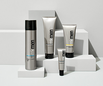 The MKMen Skin Care set in gray tubes on a gray background with a dollop of shave foam