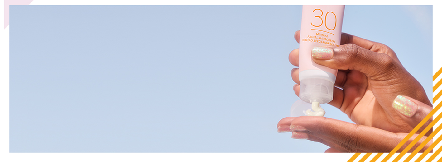 A dark skin-toned hand delicately squeezing product into other hand against a vibrant blue background.