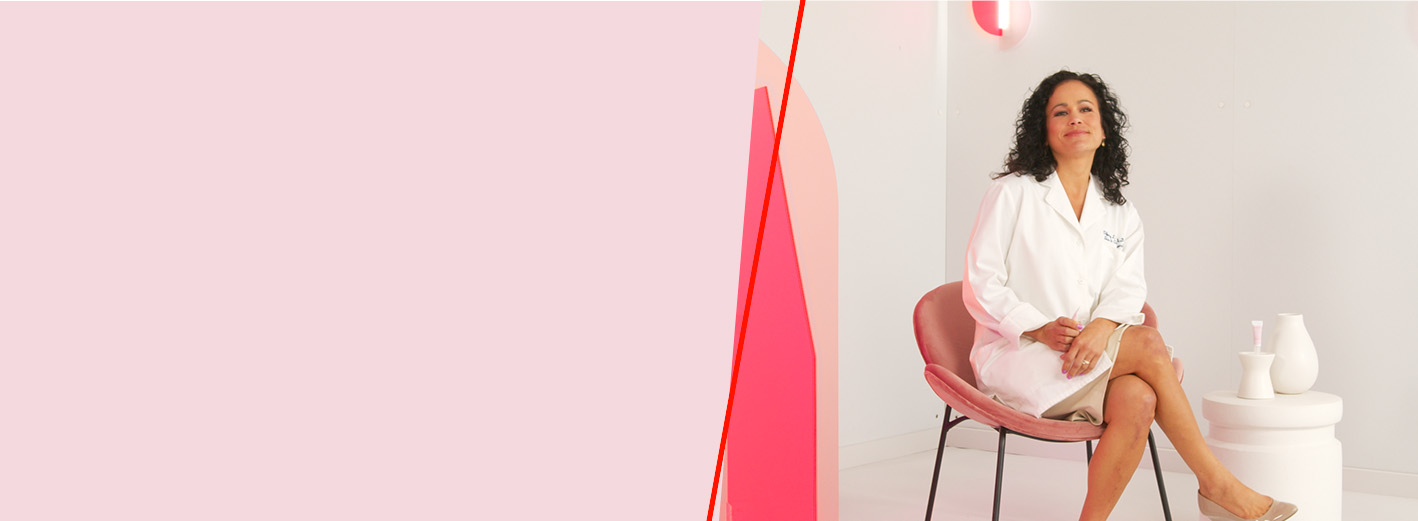 Mary Kay scientist sits in a pink chair against a white background with pink lights and divider.