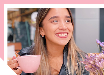 Closeup of Andrea holding a pink coffee mug