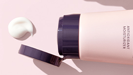 An open TimeWise Antioxidant Moisturizer next to a dime-sized dollop of product on a light pink background