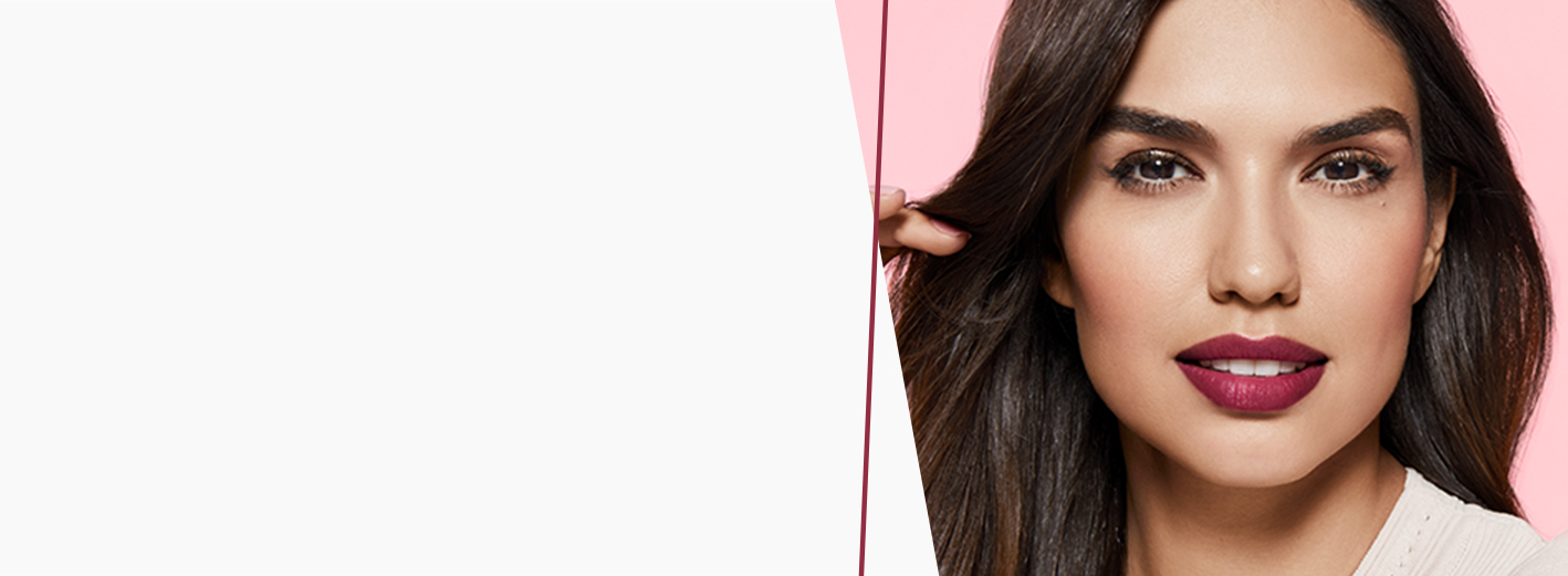 A brunette woman with bold berry lips playing with her hair on a pink background