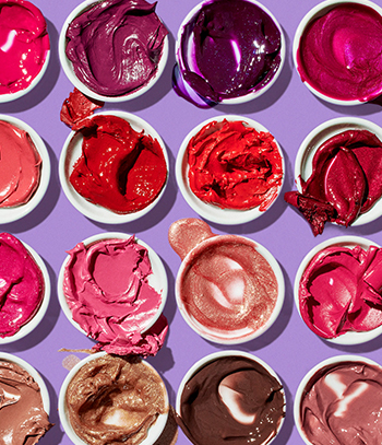Pots of Mary Kay lip colour with overflowing product smears against purple background.