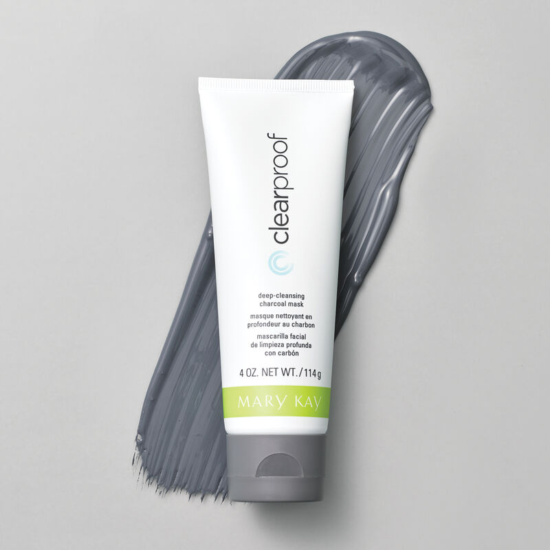A bottle of Mary Kay Clear Proof Deep Cleansing Charcoal Mask rests atop a smear of its creamy grey contents