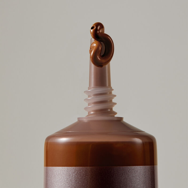 Macro view of TimeWise Luminous 3D Foundation needle-nose applicator dispensing Deep 10 shade