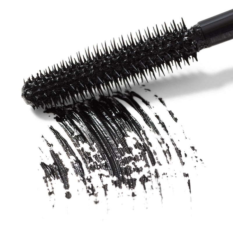 Close-up hero image of Mary Kay Great Heights Waterproof Mascara wand swiping a black product rub against a white surface&nbsp;