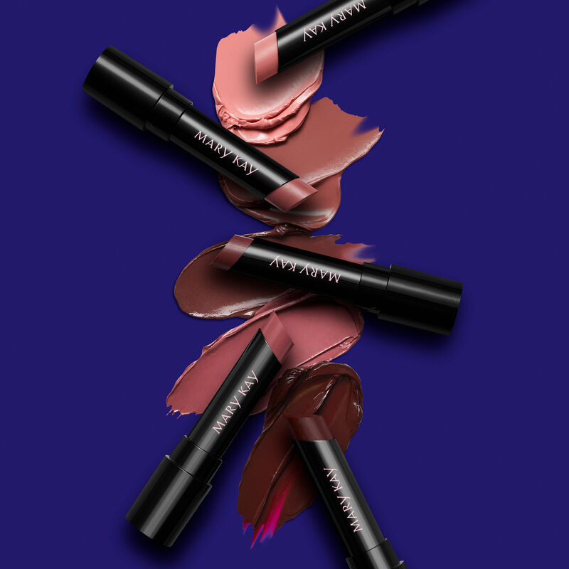 Uncapped tubes of Mary Kay Supreme Hydrating Lipstick in five shades on product rubs against dark purple background