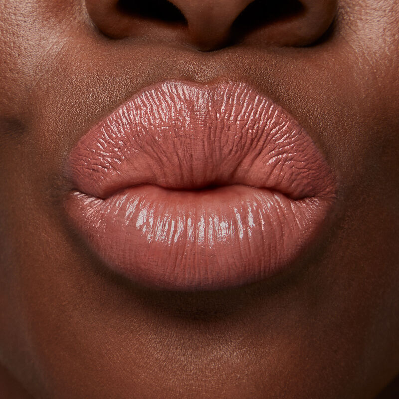 Close up of deep skinned model&rsquo;s puckered lips wearing Mary Kay Supreme Hydrating Lipstick in shade Hushed Blush.
