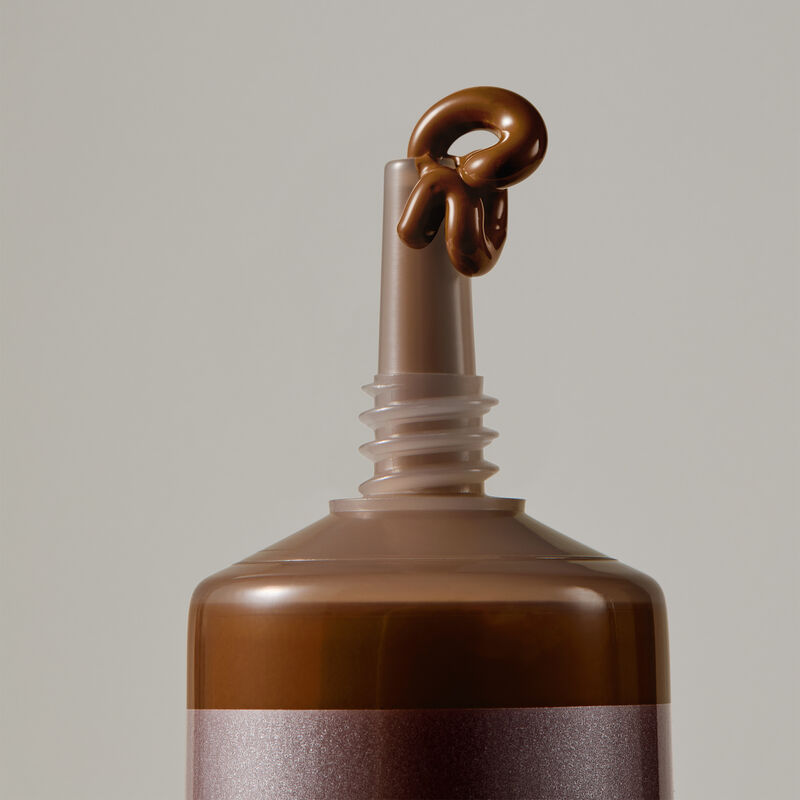 Macro view of TimeWise Luminous 3D Foundation needle-nose applicator dispensing Deep 13 shade