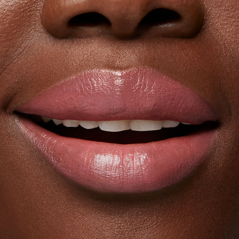 Close up of deep skinned model&rsquo;s slightly smiling lips wearing Mary Kay Supreme Hydrating Lipstick in shade Mauve Crush.