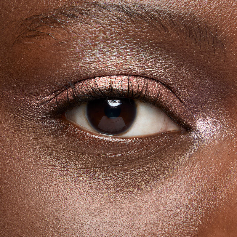 A model with a deep skin tone and brown eyes wears shade Copper Nova.