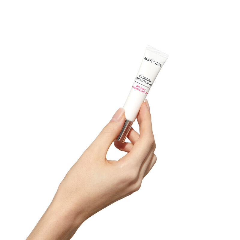 Fairskinned hand holding tube of Mary Kay Clinical Solutions Dynamic Wrinkle Limiter against a plain background