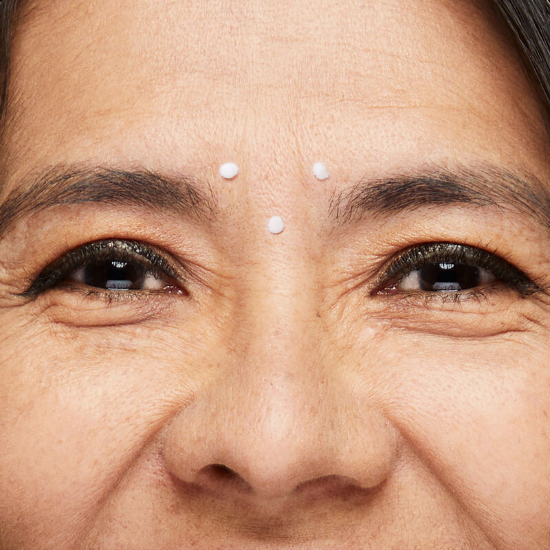 Closeup image of Dynamic Wrinkle Limiter placed in dots between eyebrows of mature brunette woman with smiling eyes