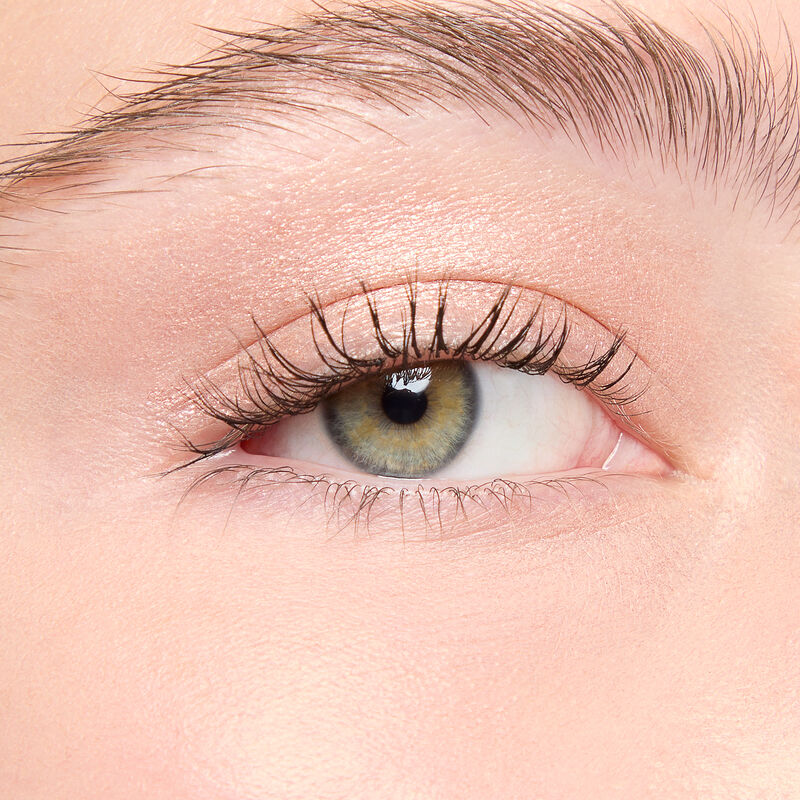 A model with a light skin tone and green eyes wears shade Golden Sunrise.