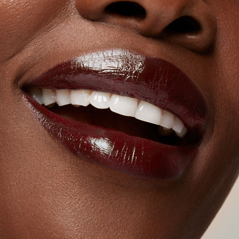 Close up of deep skinned model&rsquo;s smiling lips wearing Mary Kay Supreme Hydrating Lipstick in shade Black Cherry.