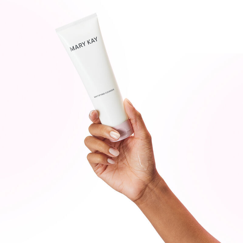 Main tenant un tube du Nettoyant matifiant Mary Kay avec un frottis du produit sur la main