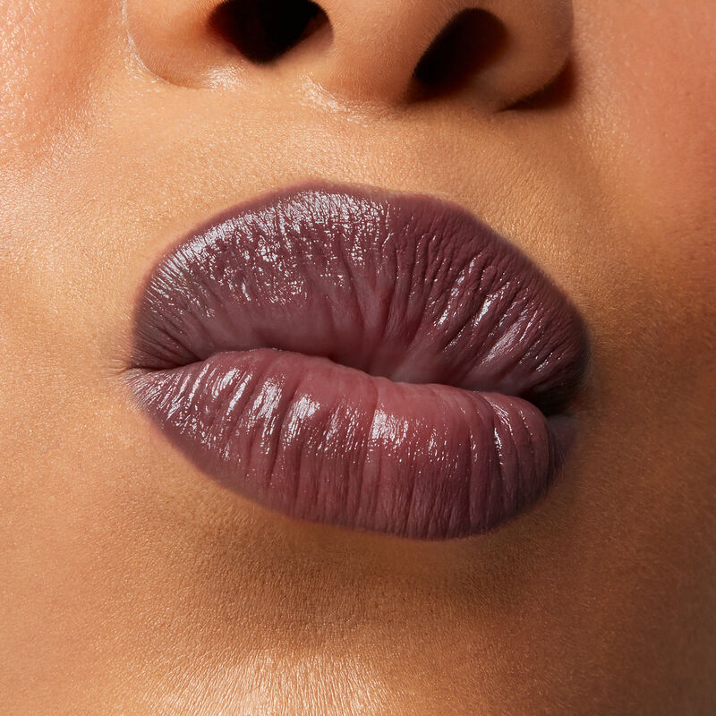 Close up of medium skinned model&rsquo;s puckered lips wearing Mary Kay Supreme Hydrating Lipstick in shade Toasted Plum.