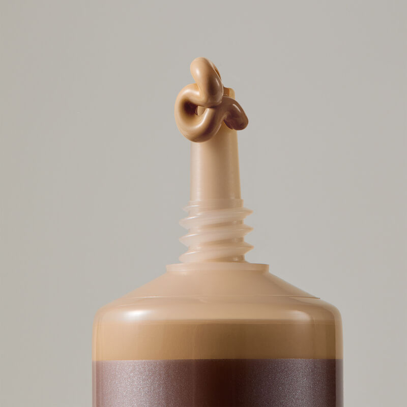 Macro view of TimeWise Luminous 3D Foundation needle-nose applicator dispensing Medium 8 shade