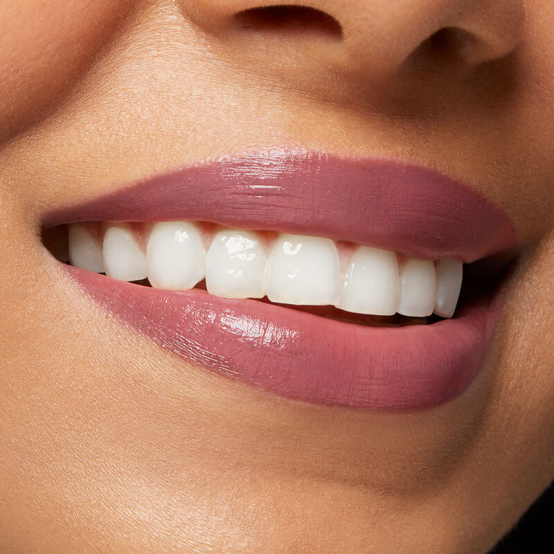 Close up of medium skinned model&rsquo;s smiling lips wearing Mary Kay Supreme Hydrating Lipstick in shade Mauve Crush.