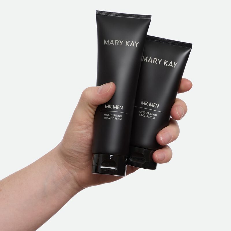Hand shown holding a tube of MKMen Moisturizing Shave Cream and a tube of limitededition MKMen Invigorating Face Scrub