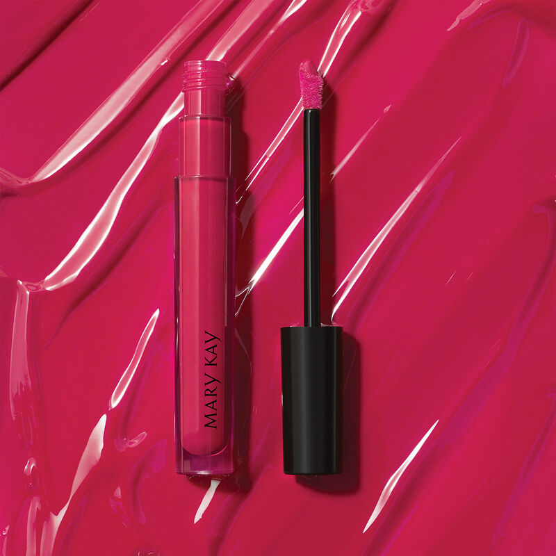 Open tube of Mary Kay Unlimited Lip Gloss in shade Pink Fusion against accompanying shade rub