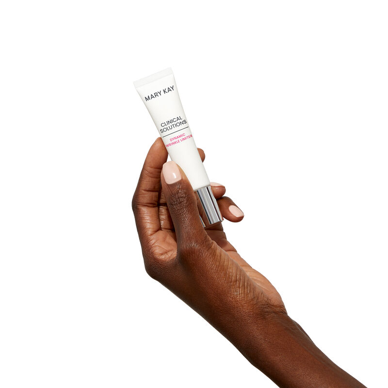 Deepskinned hand holding tube of Mary Kay Clinical Solutions Dynamic Wrinkle Limiter against a plain background