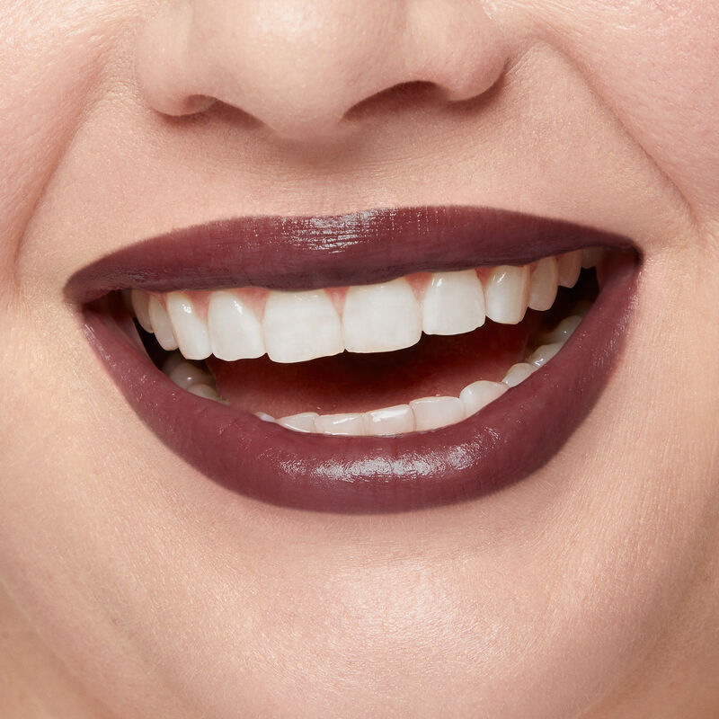 Close up of fair skinned model&rsquo;s smiling lips wearing Mary Kay Supreme Hydrating Lipstick in shade Toasted Plum.