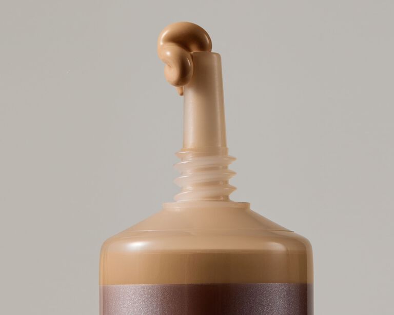 Close-up of a foundation tube with a small amount of product dispensed from the nozzle
