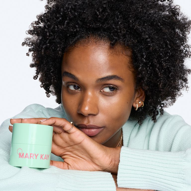 Woman behind green jar of Mary Kay Melt-In Cleansing Balm