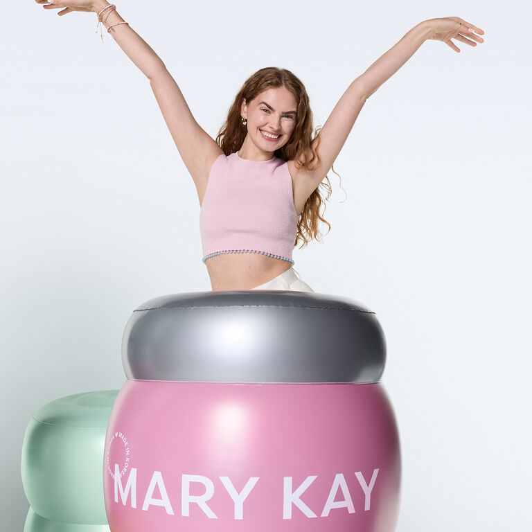 Woman cheering behind giant jar of Mary Kay Collagen Moisturizing gel