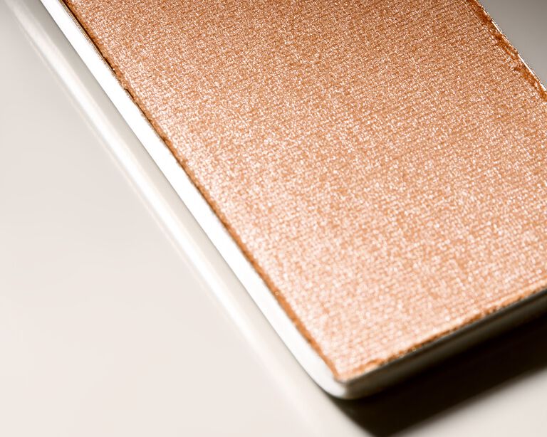Close-up of a metal makeup pan holding shimmery highlighter