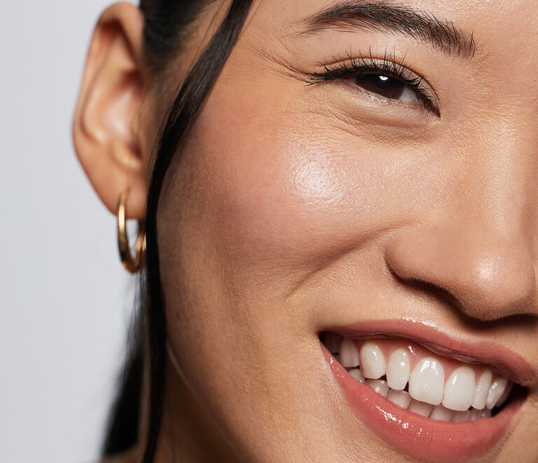 Close-up of a model with gold hoop earrings smiling
