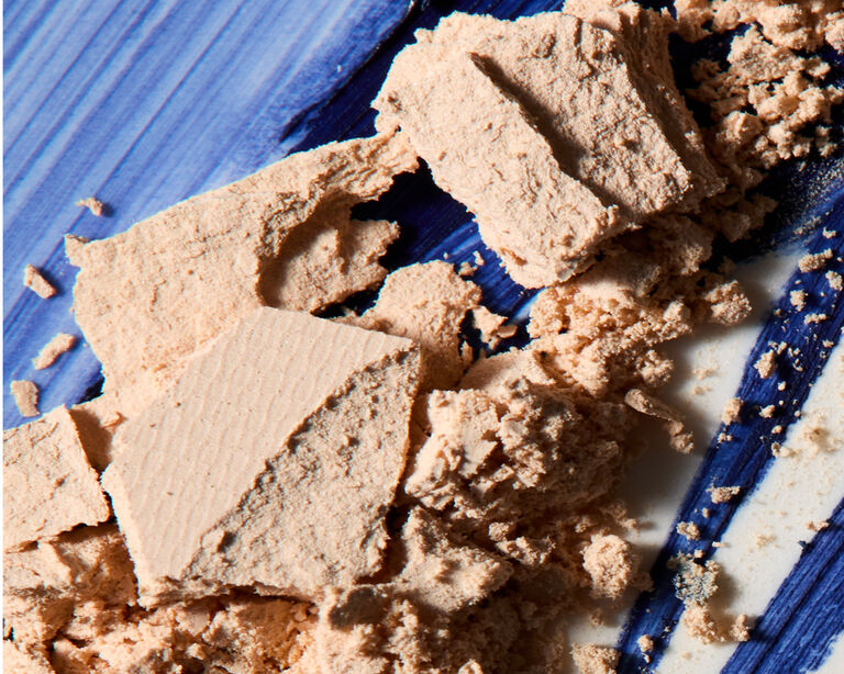 Crumbled gold powder on top of a blue swatch