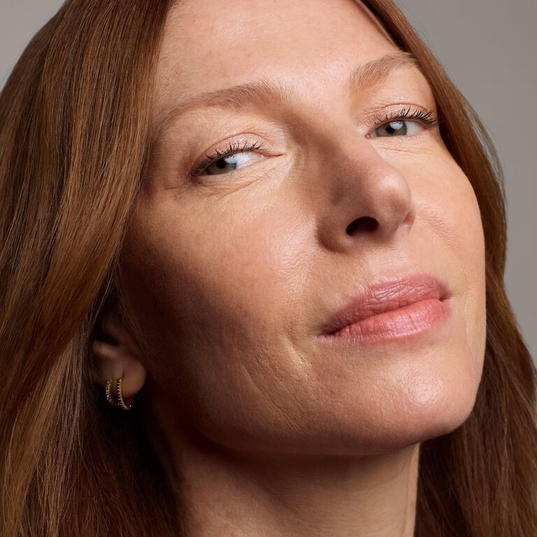 Close-up of a mature model applying concealer under her eye