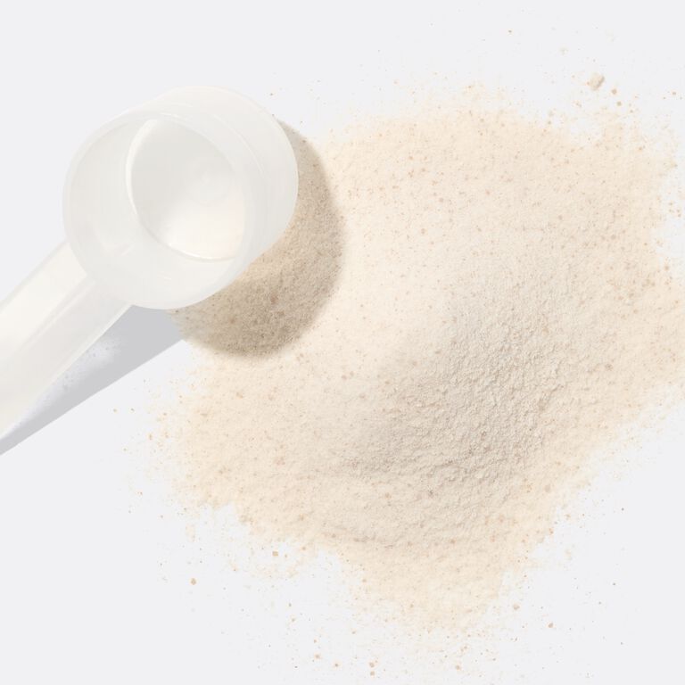 White scoop tipped over beside a small pile of Mary Kay Collagen powder on a plain light background.