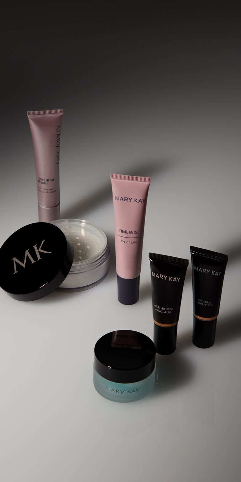 Metallic purple tube of eye cream next to an open container of loose powder and a pink tube of eye cream