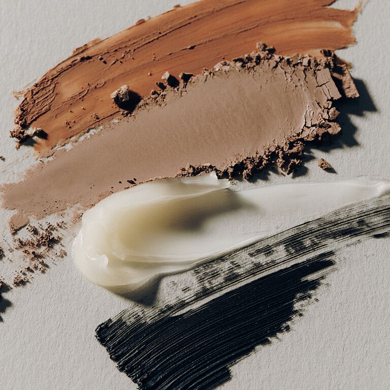 Product swatch featuring brown eye shadow, clear brow gel and black mascara