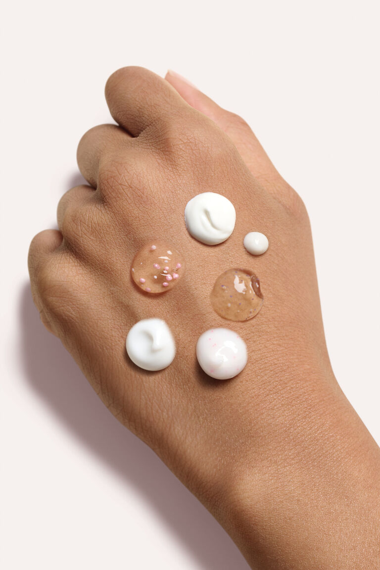 A woman's hand with drops of Mary Kary TimeWise products on it.
