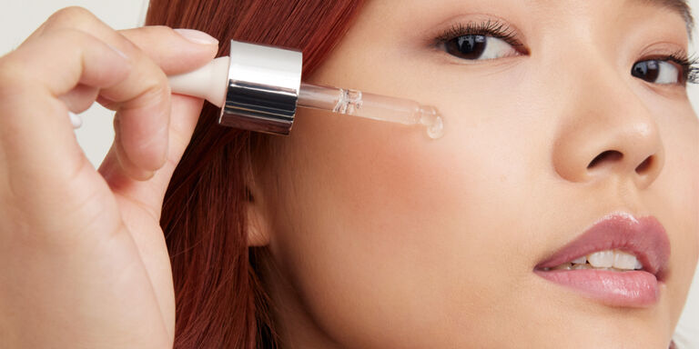 Model applying serum to her cheek