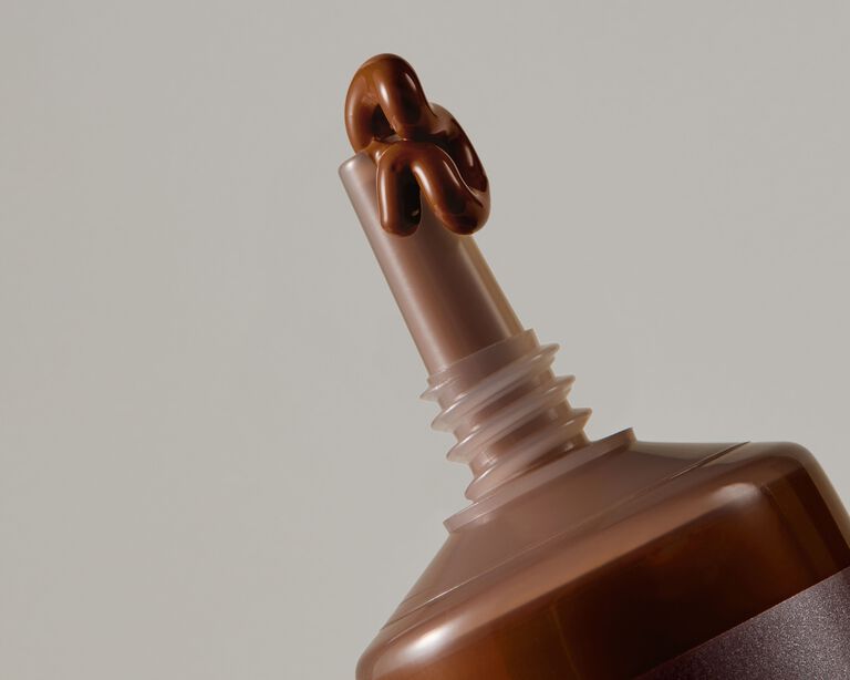 Close-up of a foundation tube with a small amount of product dispensed from the nozzle
