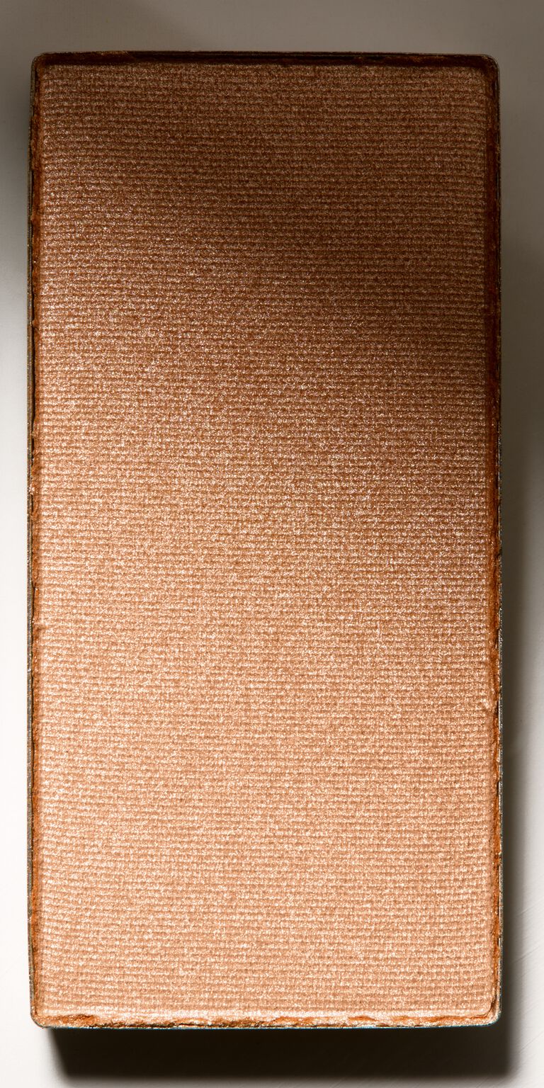 Close-up of a metal makeup pan holding shimmery highlighter