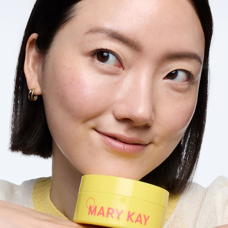Smirking woman holding yellow jar of Mary Kay Snail Gel Face Patches