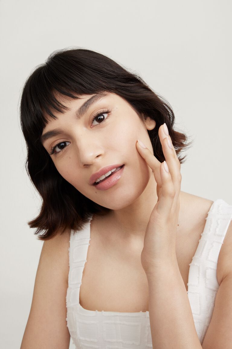 Woman applying skincare to her cheek