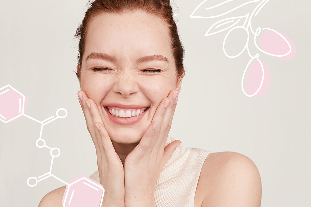 Une femme sourit avec les yeux ferm&eacute;s et les deux mains sur le visage. Elle est entour&eacute;e d&rsquo;illustrations repr&eacute;sentant des ingr&eacute;dients utilis&eacute;s dans les produits de soins de la peau.