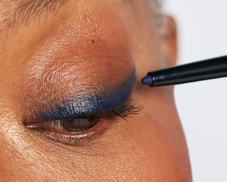 Close-up of model applying blue eyeliner