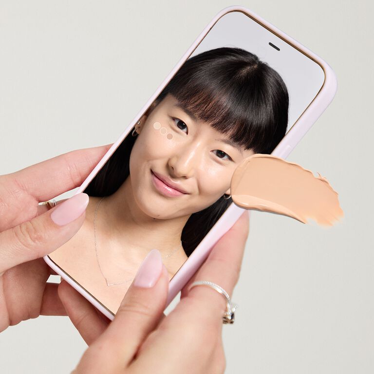 Des mains tiennent un appareil mobile montrant l&rsquo;Outil de s&eacute;lection de fond de teint Mary Kay. 