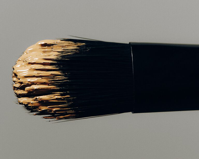 Makeup brush covered in a light shade of concealer 